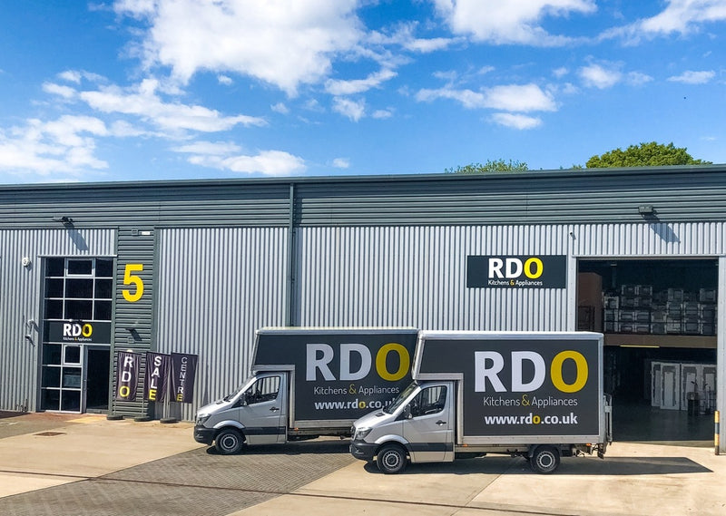RDO Kitchens & Appliances warehouse with branded delivery vans parked outside under a clear blue sky.
