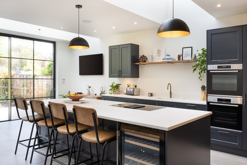 Modern open-plan kitchen with a large island, built-in wine cooler, integrated ovens, pendant lighting, and bar seating.